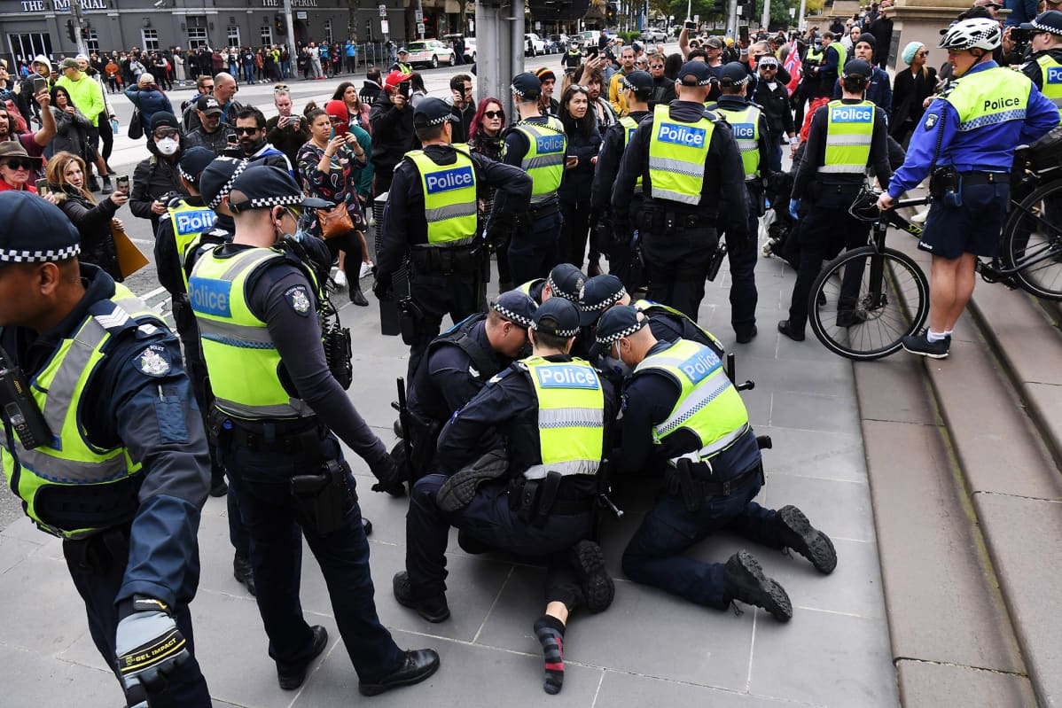 Kuvassa poliisi pitelee koronaviruksen vastaisia toimia vastustavaa mielenosoittajaa maassa.
