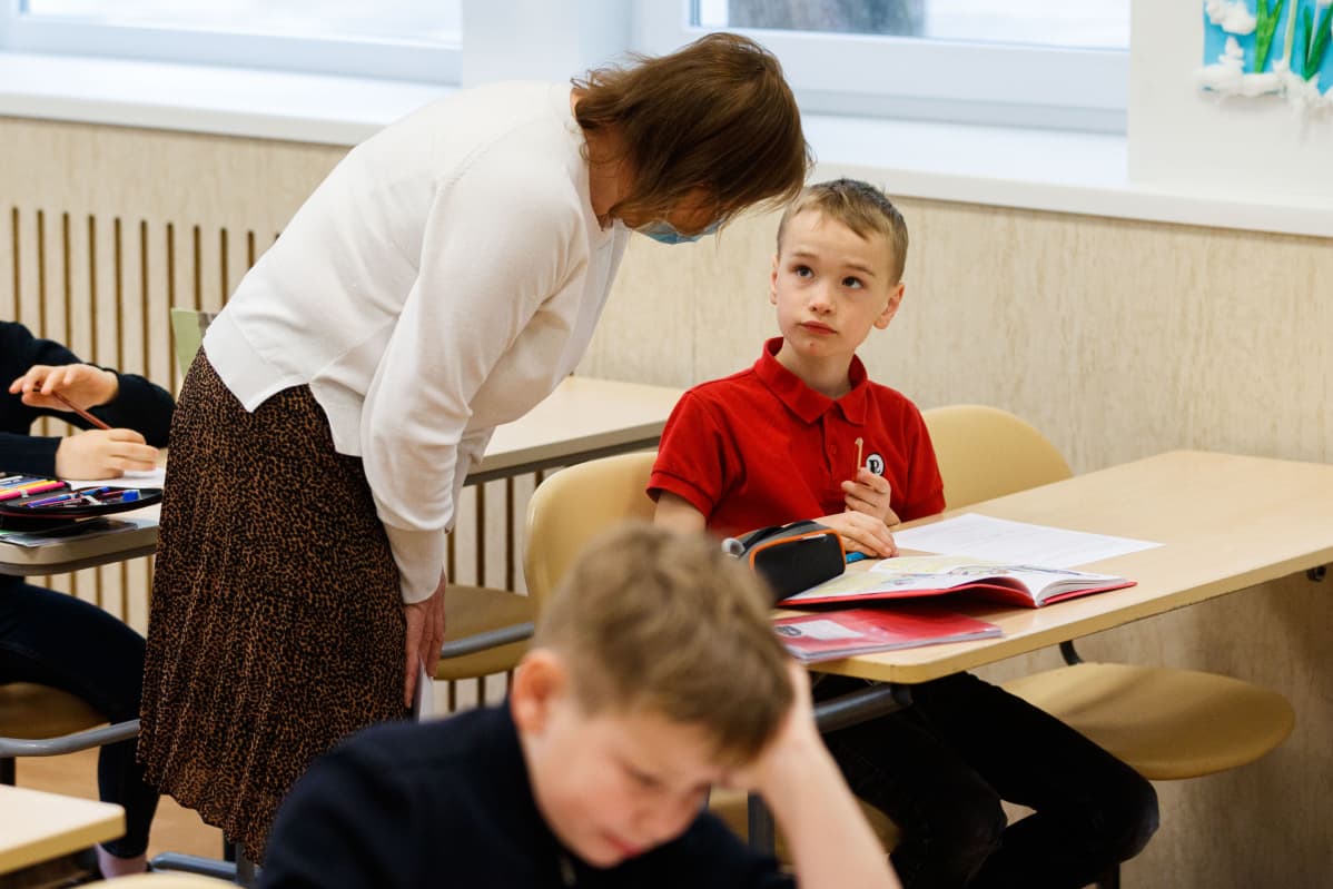 Opettaja Marianna Lenzo neuvoo ekaluokkalaista Martti Hiobia.