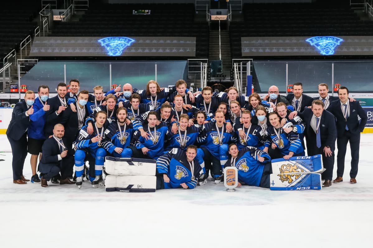 Nuorten Leijonien pronssijoukkue yhteiskuvassa jäällä.