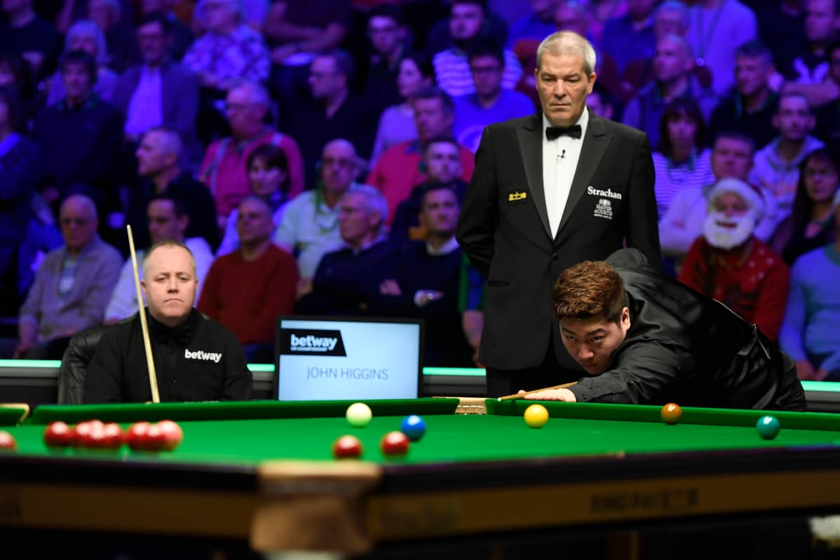 John Higgins istuu ja katselee Yan Bingtaon lyöntiä UK Championship -turnauksen puolivälierässä joulukuussa 2019. Yan voitti ottelun erin 6–3