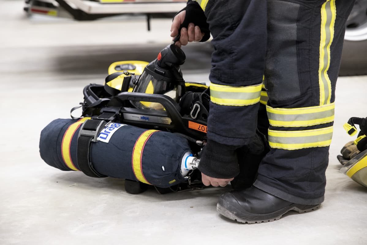 Palomiehen kädet säätävät savusukelluksessa käytettävää paineilmapulloa.