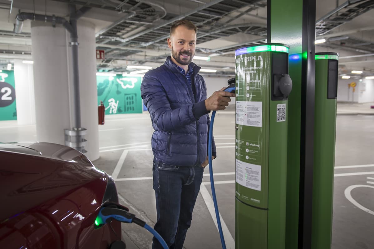 Lars Nevalainen laittaa sähköautoaan lataukseen Triplan parkkihallissa