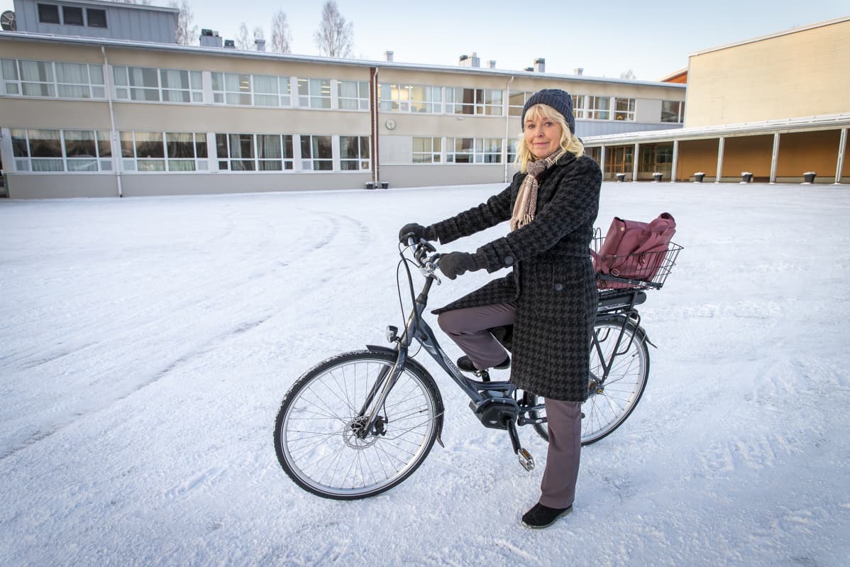 Marita Misukka-Kyyrö polkupyörän kanssa koulun edessä.