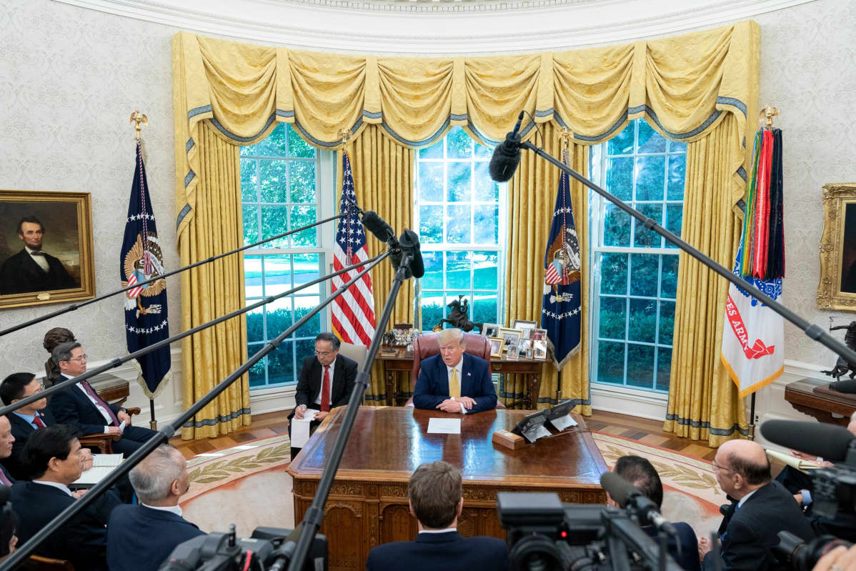 Yhdysvaltojen presidentti Donald Trump ja Kiinan varapääministeri Liu He toimittajien ympäröimänä presidentin virkahuoneessa Valkoisessa talossa.