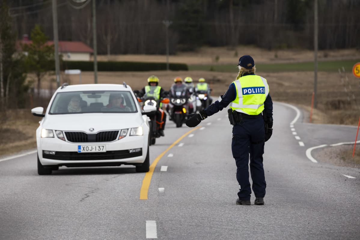 Poliisi pysäyttää auton ja moottoripyöriä Pukkilan karanteeni rajalla.