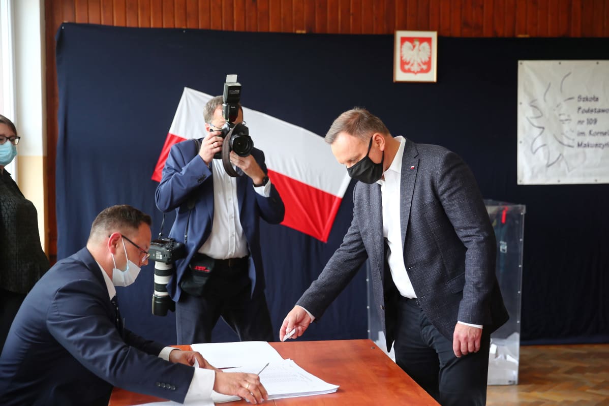 Andrzej Duda äänestää maski kasvoillaan.