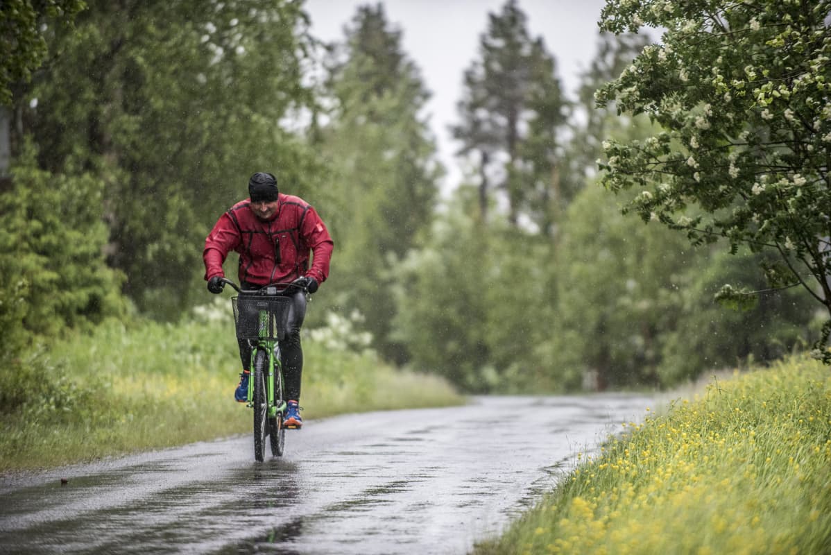 Pyöräilijä polkee sateessa.