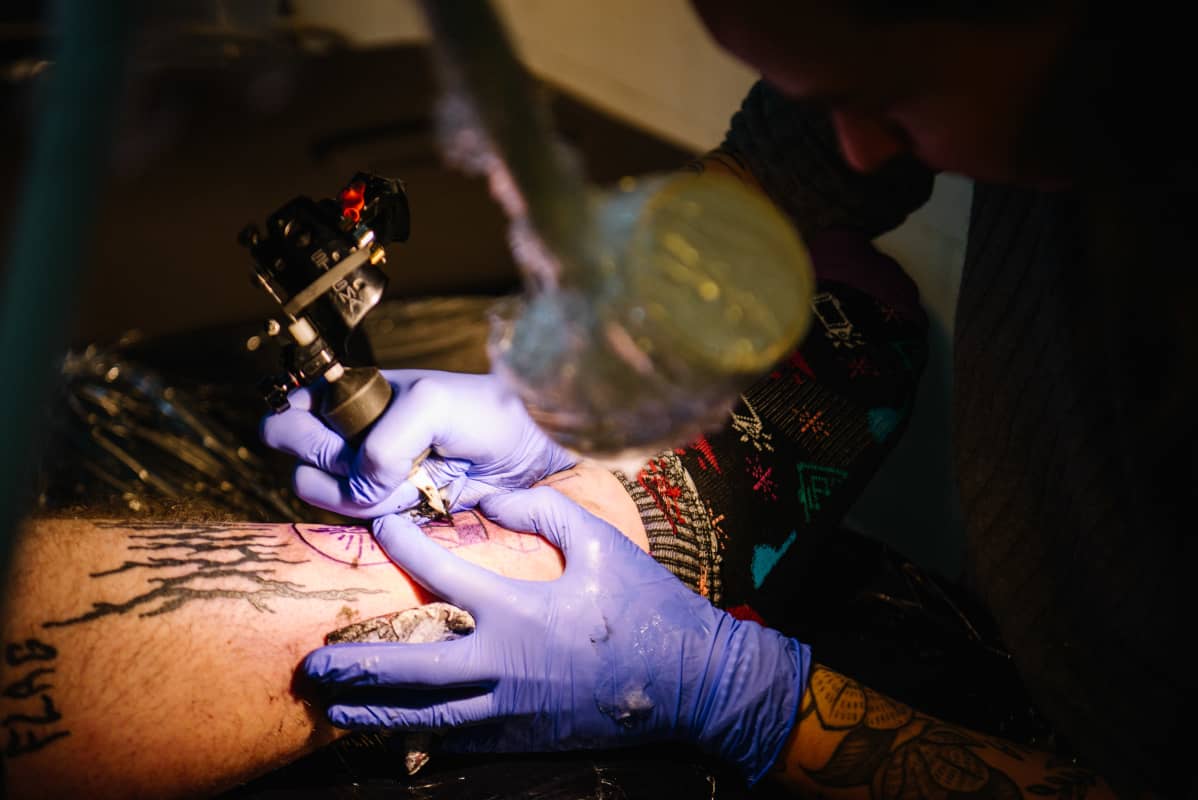 Tatuointia tehdään henkilön sääreen.