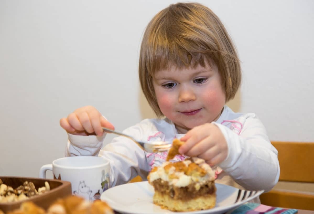 Pieni tyttö syö kakkua haarukalla.