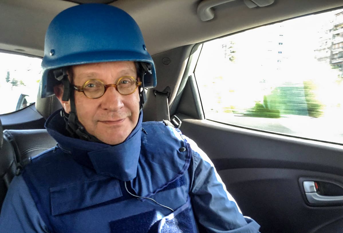 Tom Kankkonen autossa luotiliivit päällä ja kypärä päässä.
