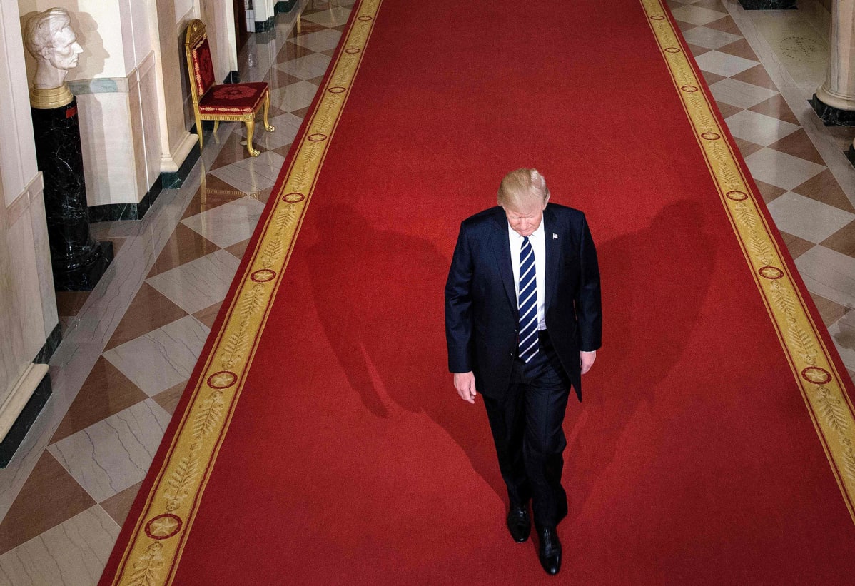 Donald Trump kävelee valkoisen talon käytävällä.