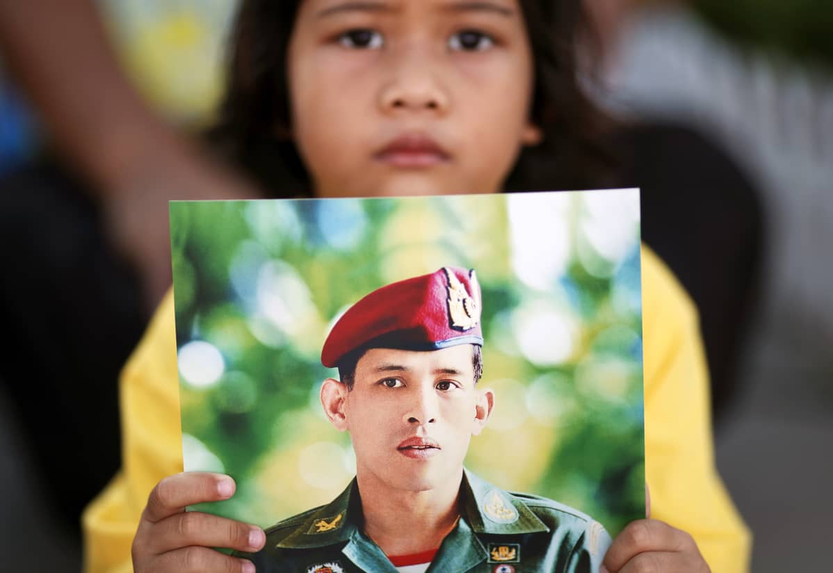 Thaityttö kunnioitti uutta kuningasta palatsin ulkopuolella Bangkokissa lauantaina.