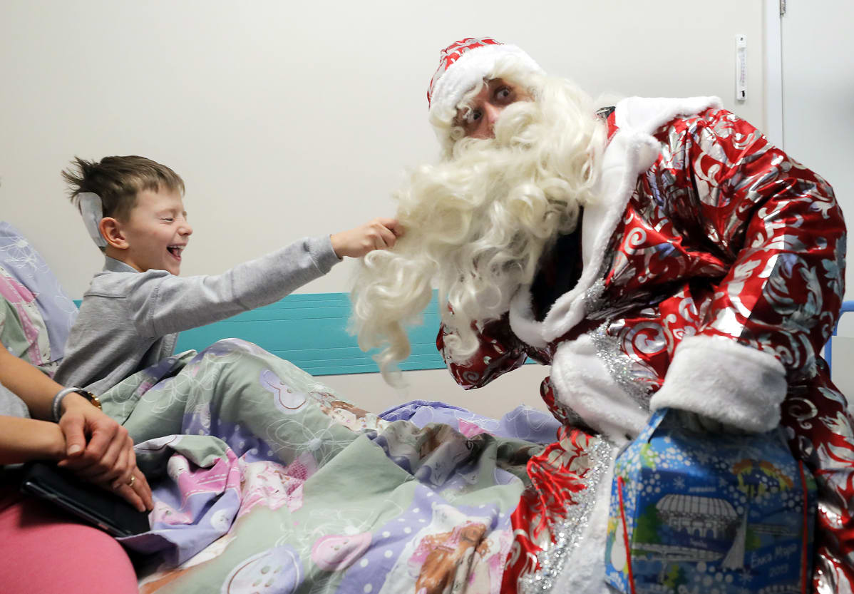Pieni potilas veti Pakkasukkoa parrasta lastensairaalassa järjestetyssä joulutapahtumassa Moskovassa Venäjällä 27. joulukuuta.