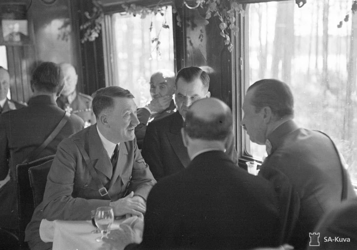 Pöydän ääressä valtakunnankansleri Adolf Hitler, pääministeri Jukka Rangell, tasavallan presidentti Risto Ryti ja marsalkka Mannerheim.