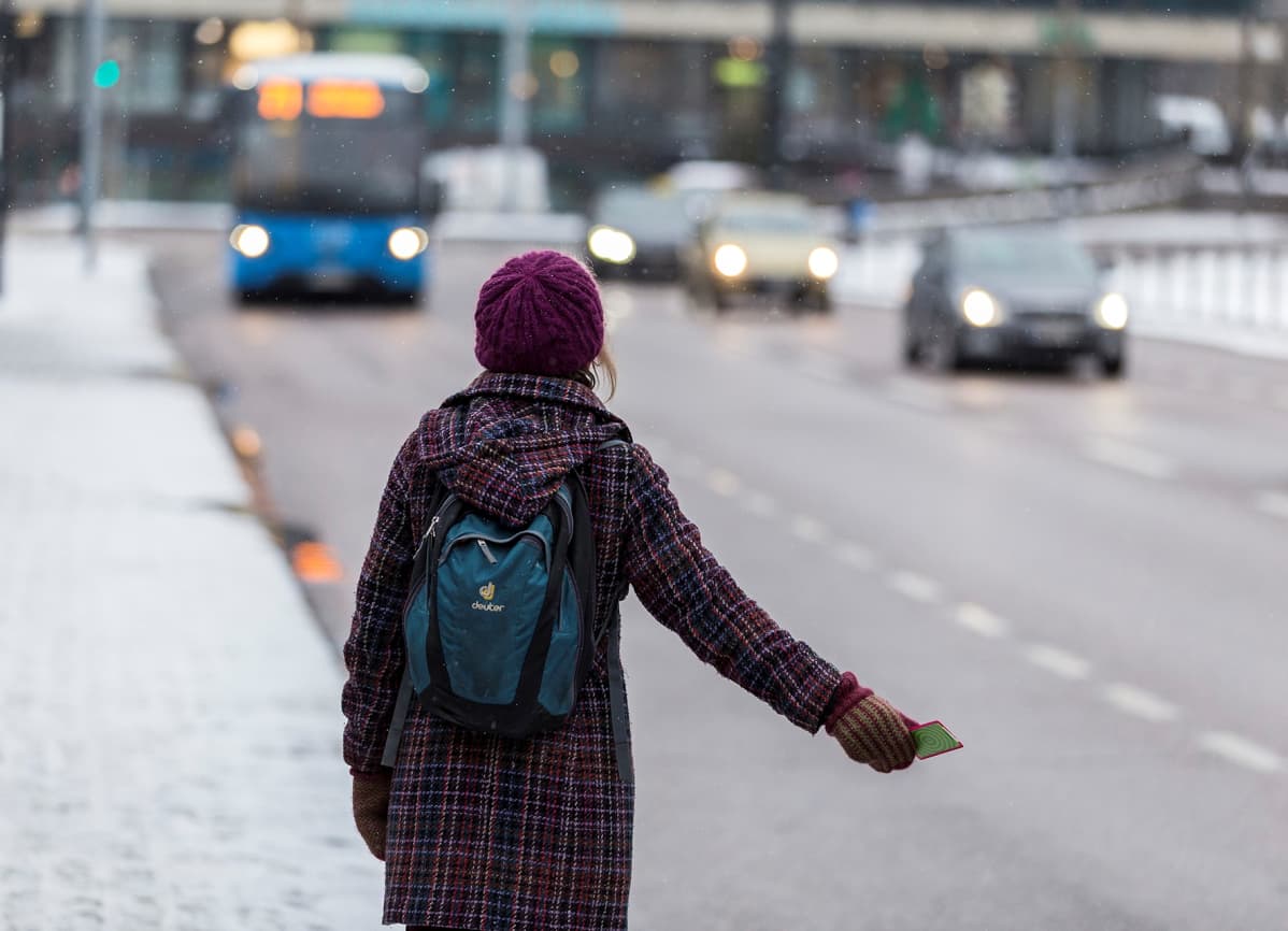 Matkustaja näyttää pysähtymismerkkiä bussille.