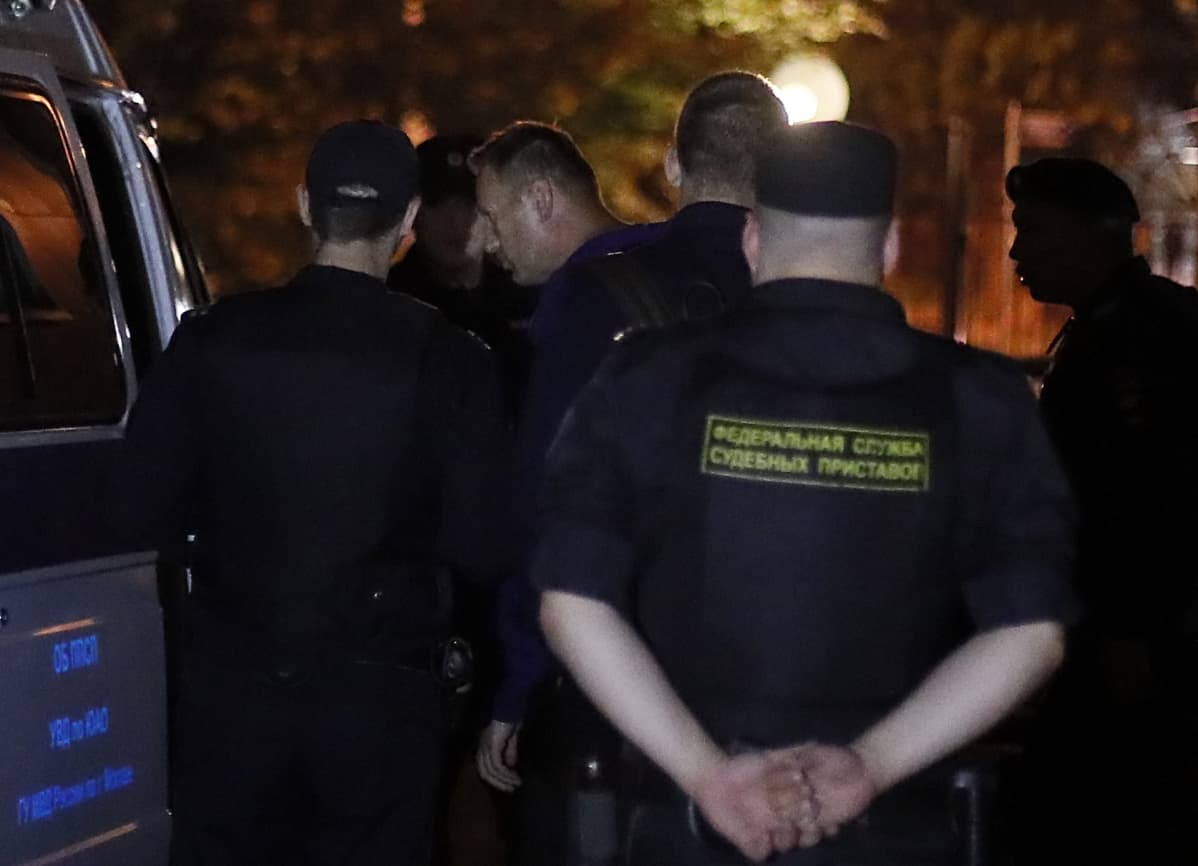 Poliisit saattavat Navalnyia autoon.