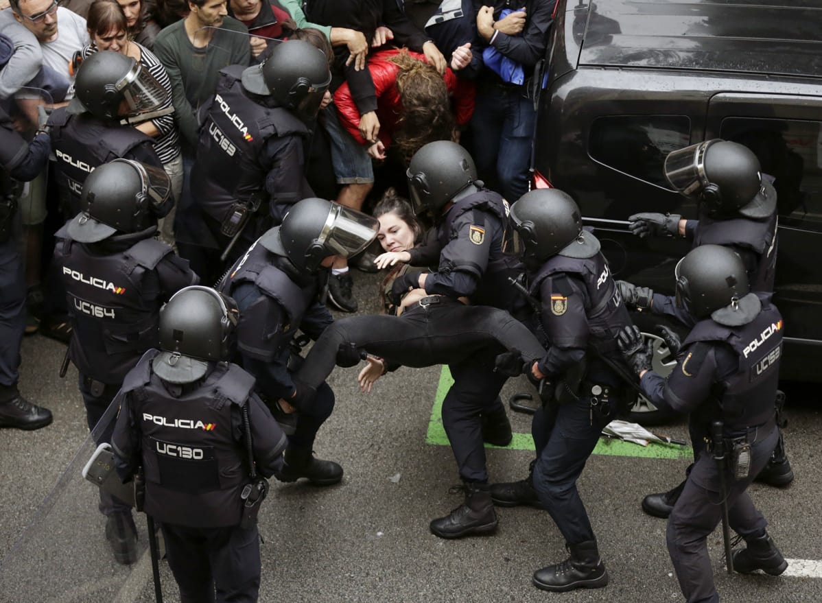 Espanjalaiset mellakkapoliisit poistivat nuoren naisen Ramon Lull koulun äänestyspaikalta 1. lokakuuta Barcelonassa.
