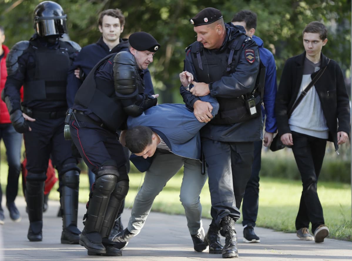 Poliisit raahaavat kiinni otettua miestä.