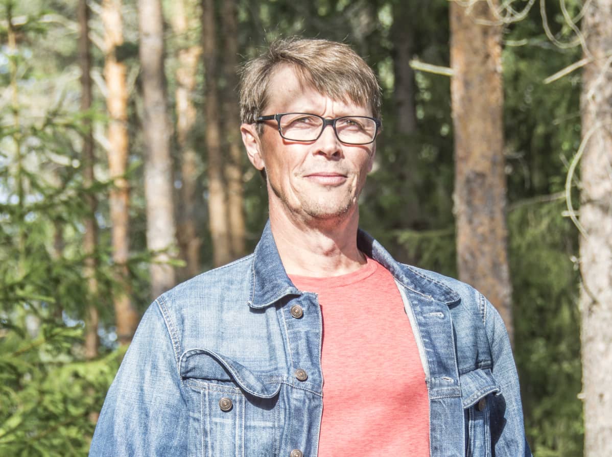 Arto Ranta-Ylitalo seisoo farkkutakki päällä metsikössä.