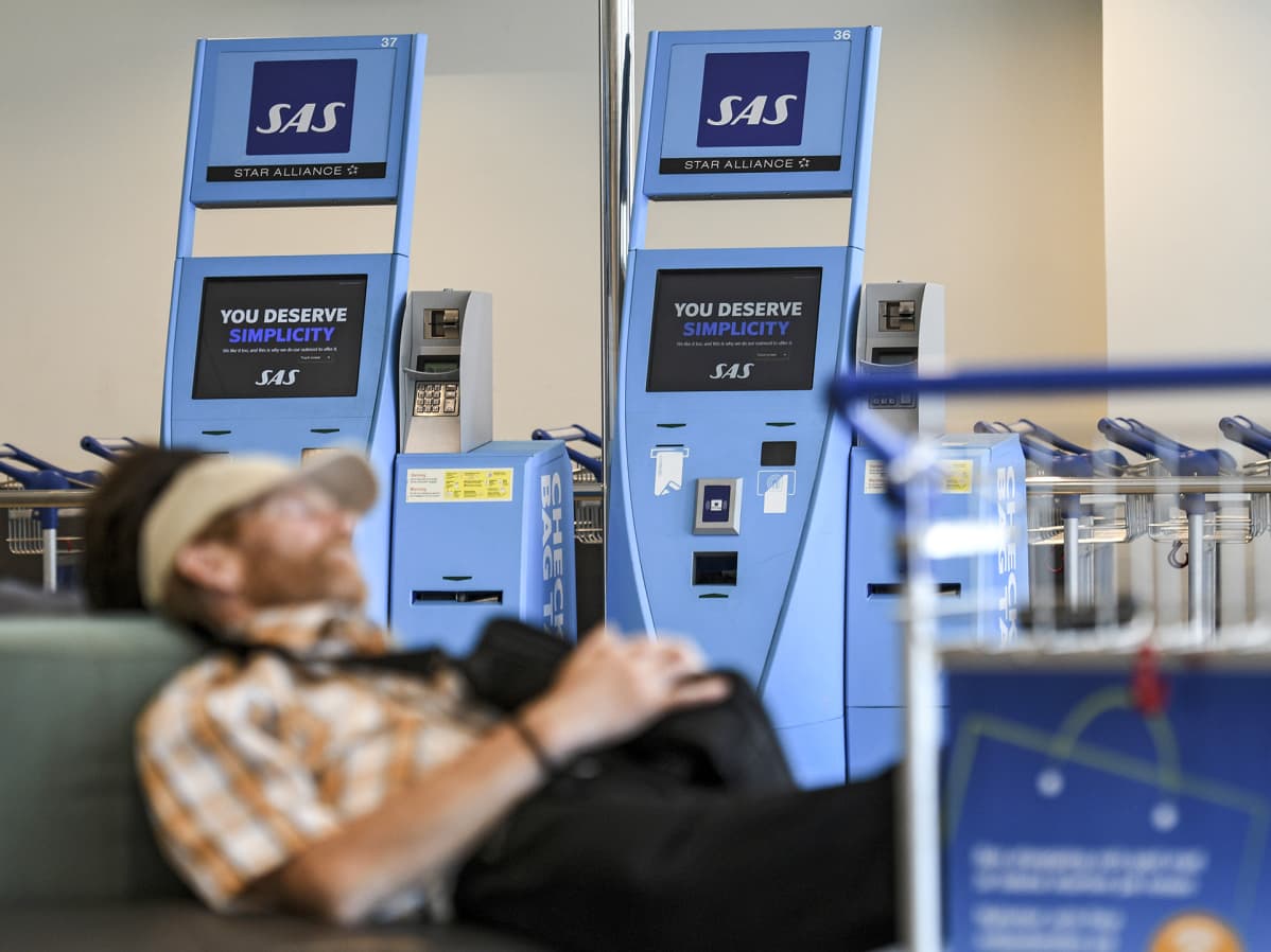 Matkustaja nukkuu lentokentän odotustilassa.