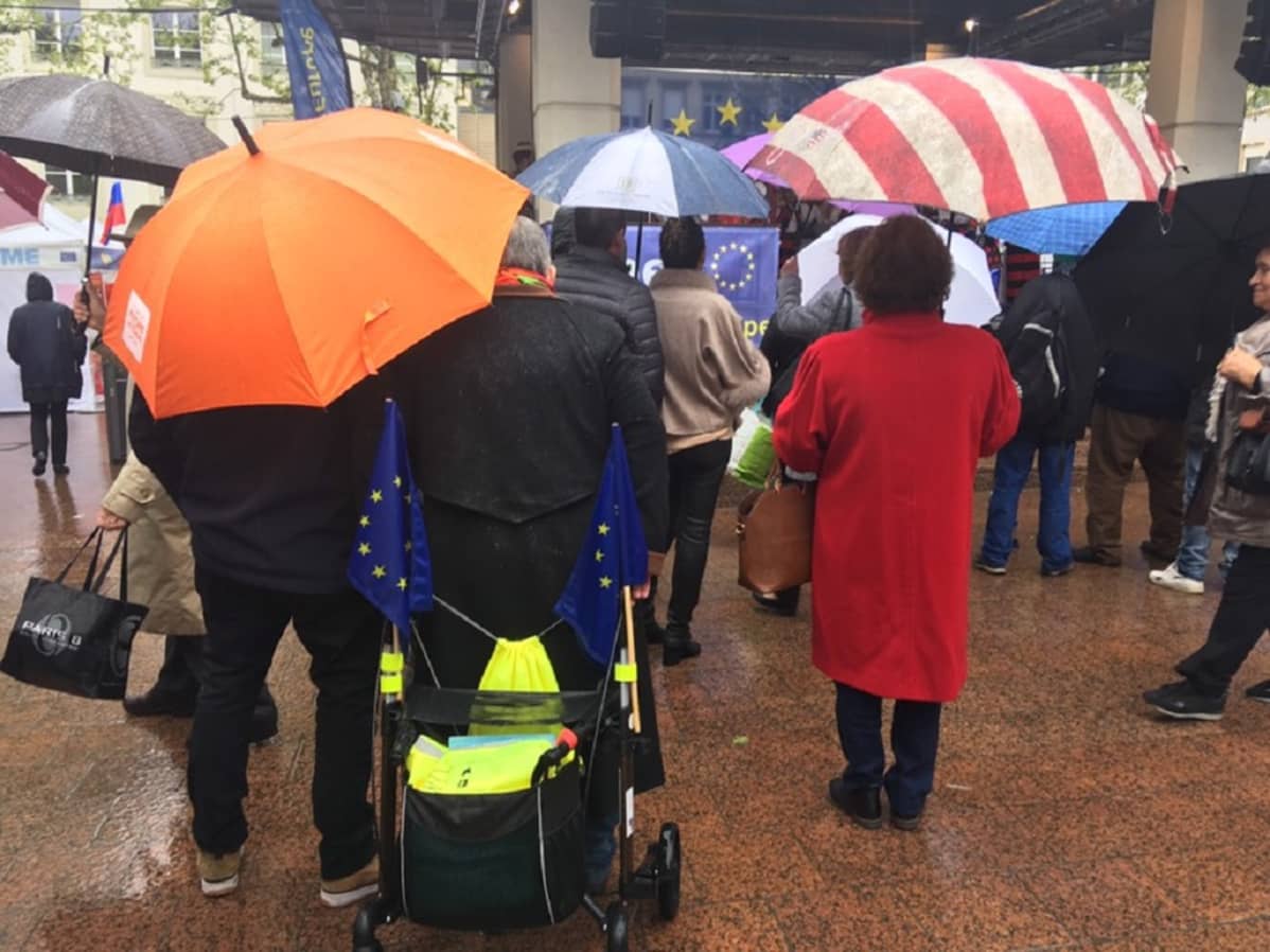 Kuvassa rollaattori, jossa EU-lippuja. Kuva Place d’Armes -keskustorilta, jossa nähdään mm. romanialaisia, irlantilaisia ja espanjalaisia tansseja.