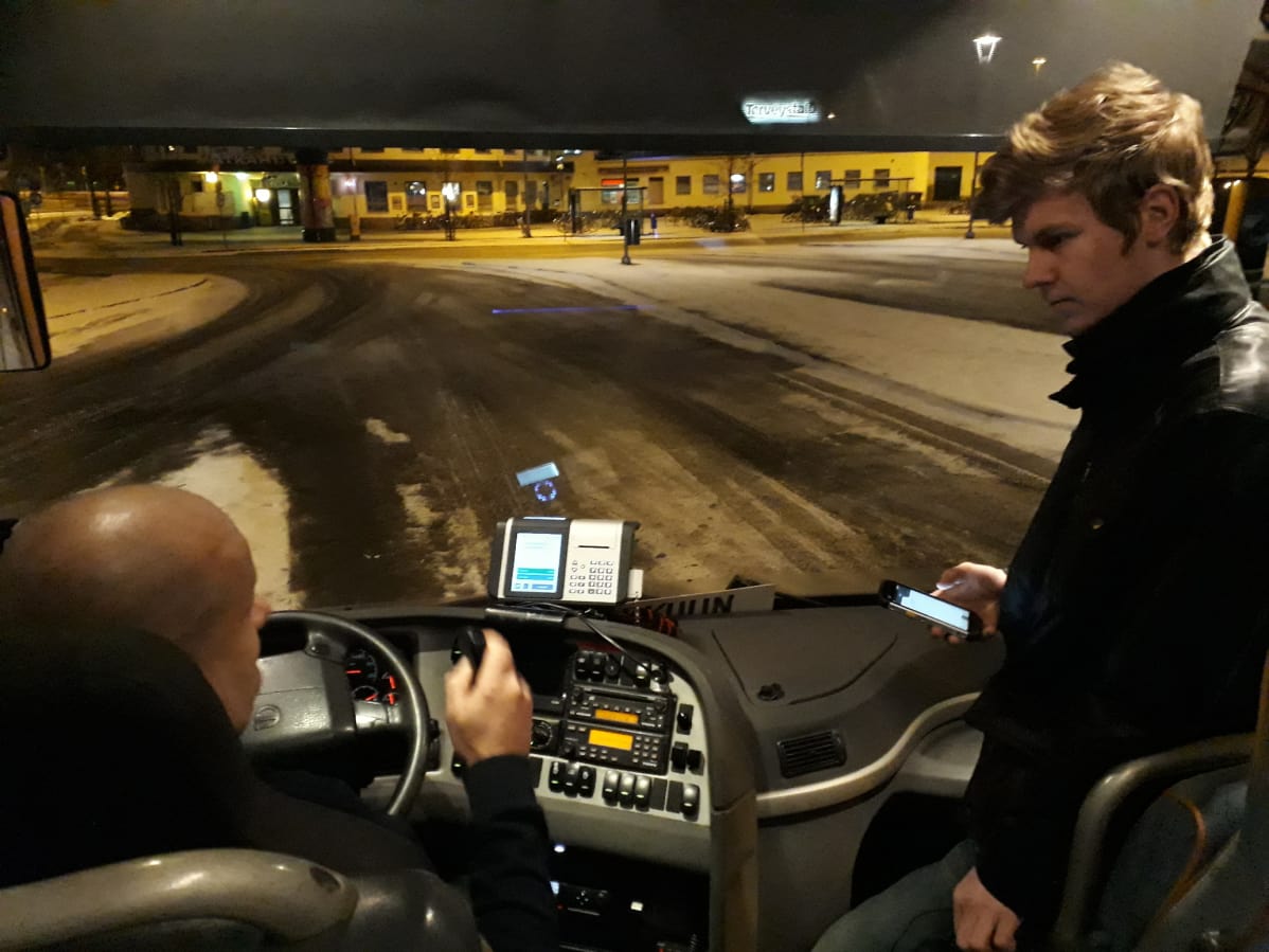 Työmatkabussiin nouseva työntekijä maksaa matkaansa.