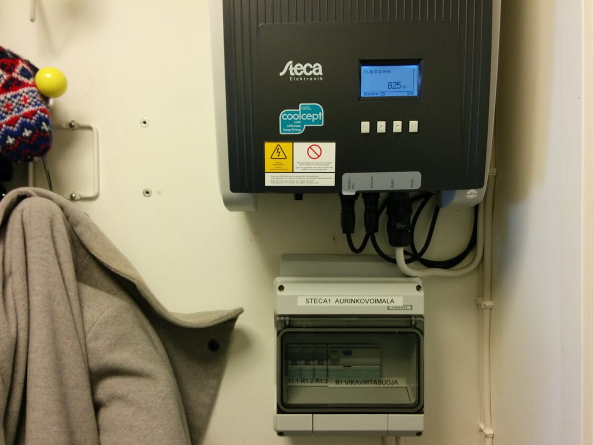Kuvassa aurinkosähköjärjestelmän invertteri, joka muun muassa mittaa sisään tulevan energian määrän. Näytössä lukee 825w.