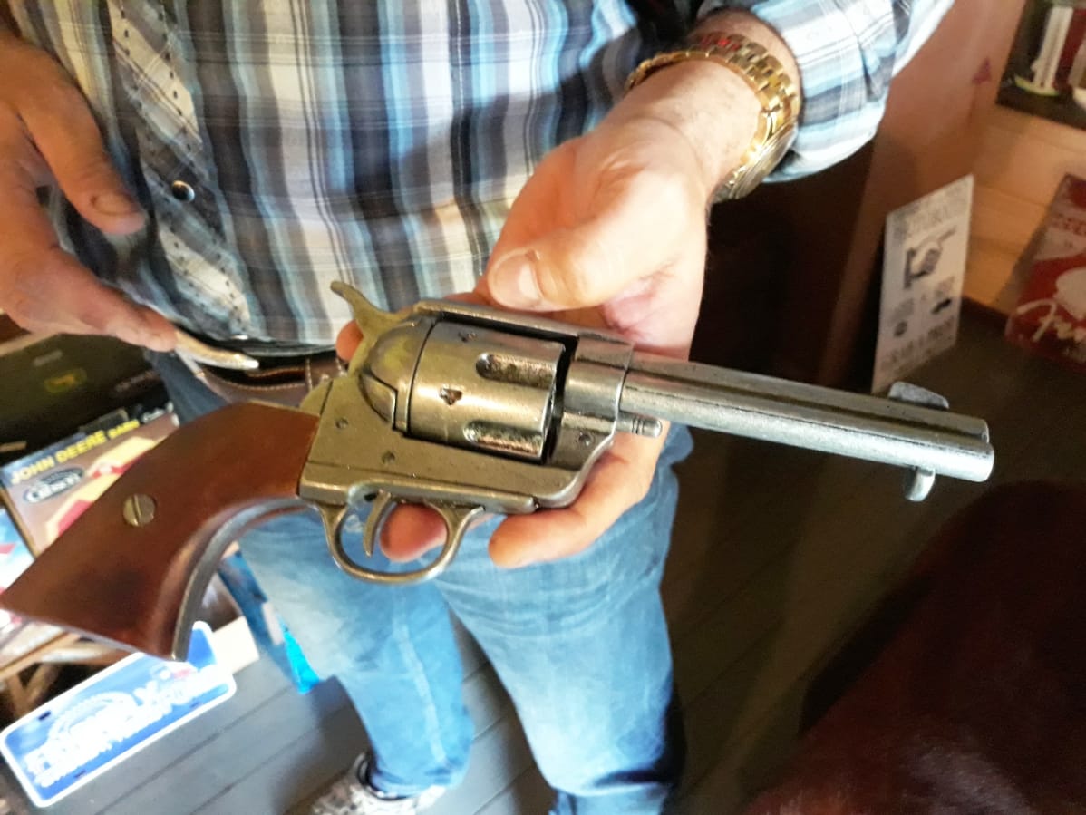 Kädessä Colt Peacemaker revolveri
