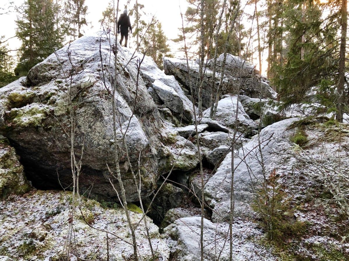 Retkeilijä suuren kivenlohkareen päällä
