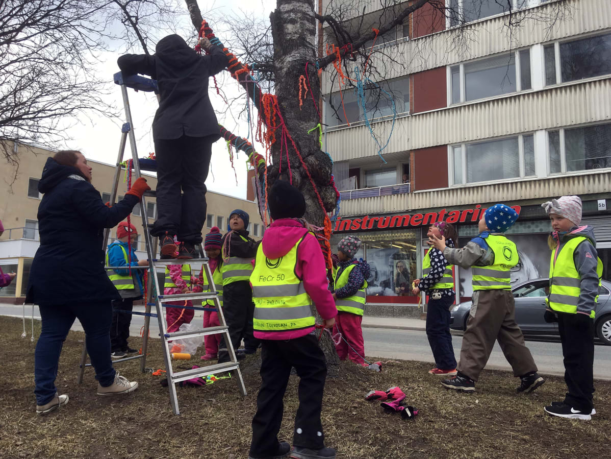 Esikoululaiset ja opettajat koristelevat puistokadun puita Kemissä.