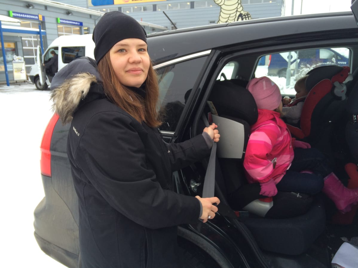 nuori nainen laittaa lapsia autoon