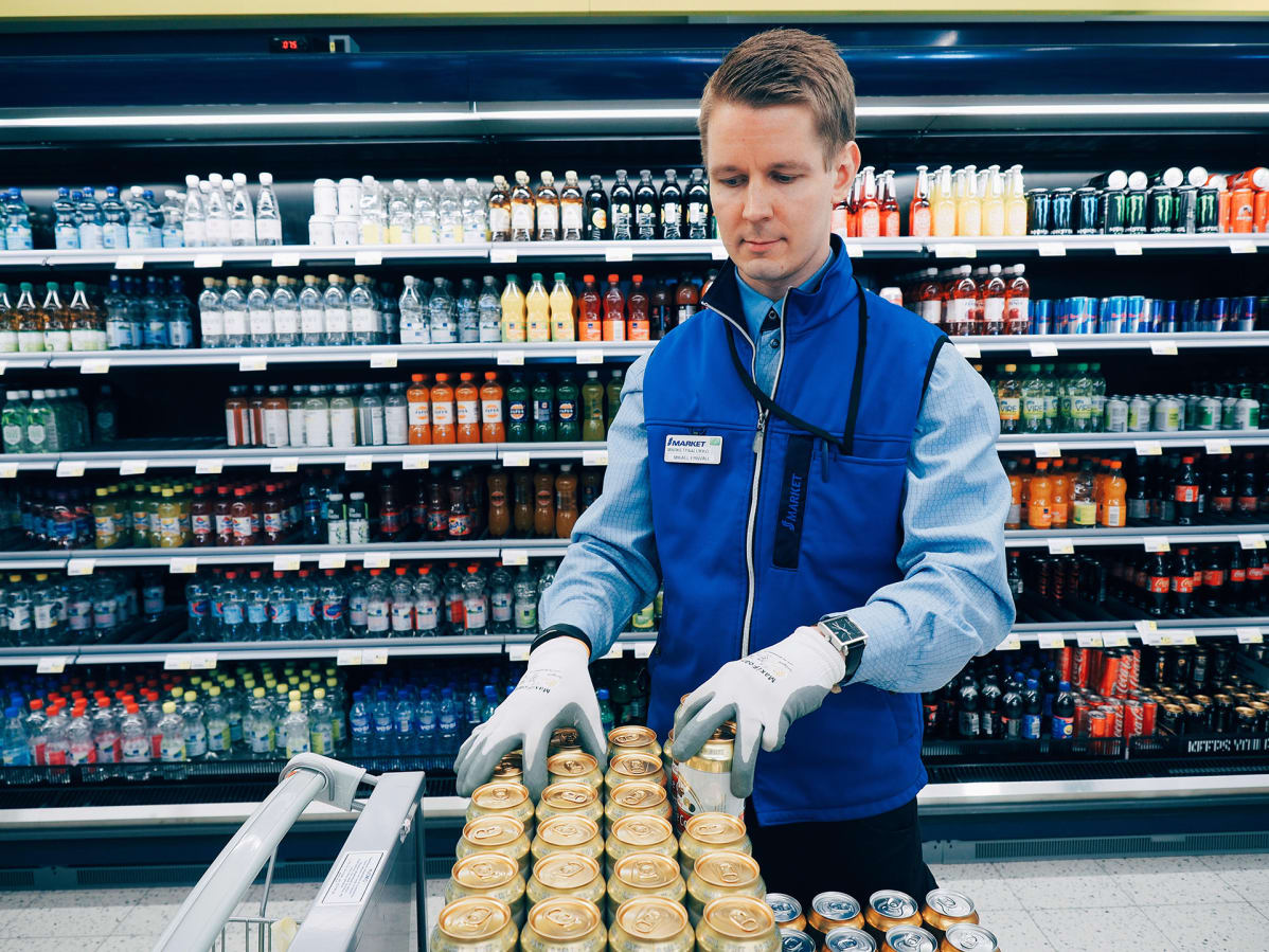 Marketpäällikkö täyttää juomahyllyjä.