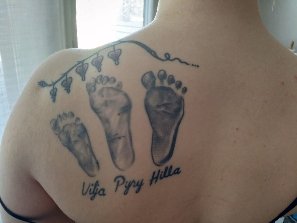Naisen selkään on tatuoitu kolme jalkapohjaa, joiden alla lukee Vilja, Pyry ja Hilla.