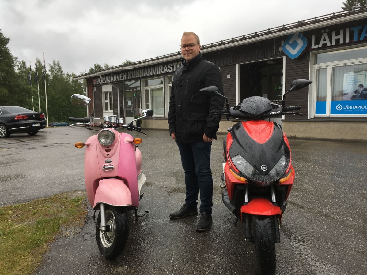 Polvijärven kunnanjohtaja Jari Tuononen seisoo kahden moposkootterin välissä.