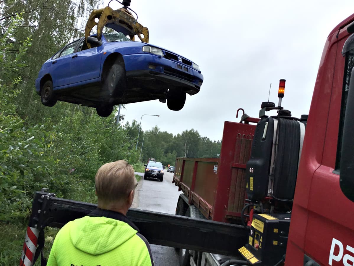 Hylättyä romuautoa kuljetetaan tienvarresta pois purkaamolle kierrätystä varten.