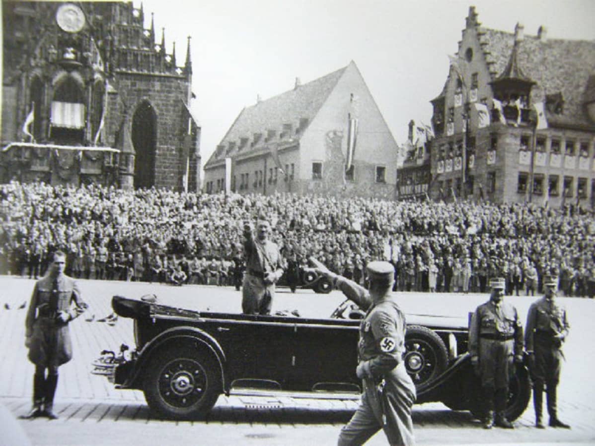 Hitler seisoo avoautossa natsitervehdystä tehden.