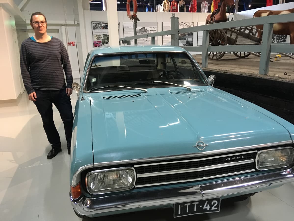 Mies seisoo automuseo Mobiliassa 1970-luvun Opelin vieressä.