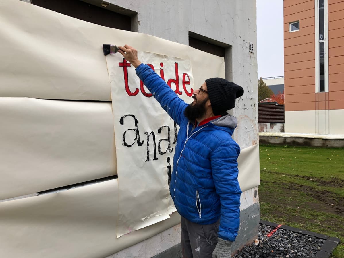 Keski-Pohjanmaan kansanopisto taideryhmä maalaa iskulauseita suojellun funkkishuoltamon seinille.