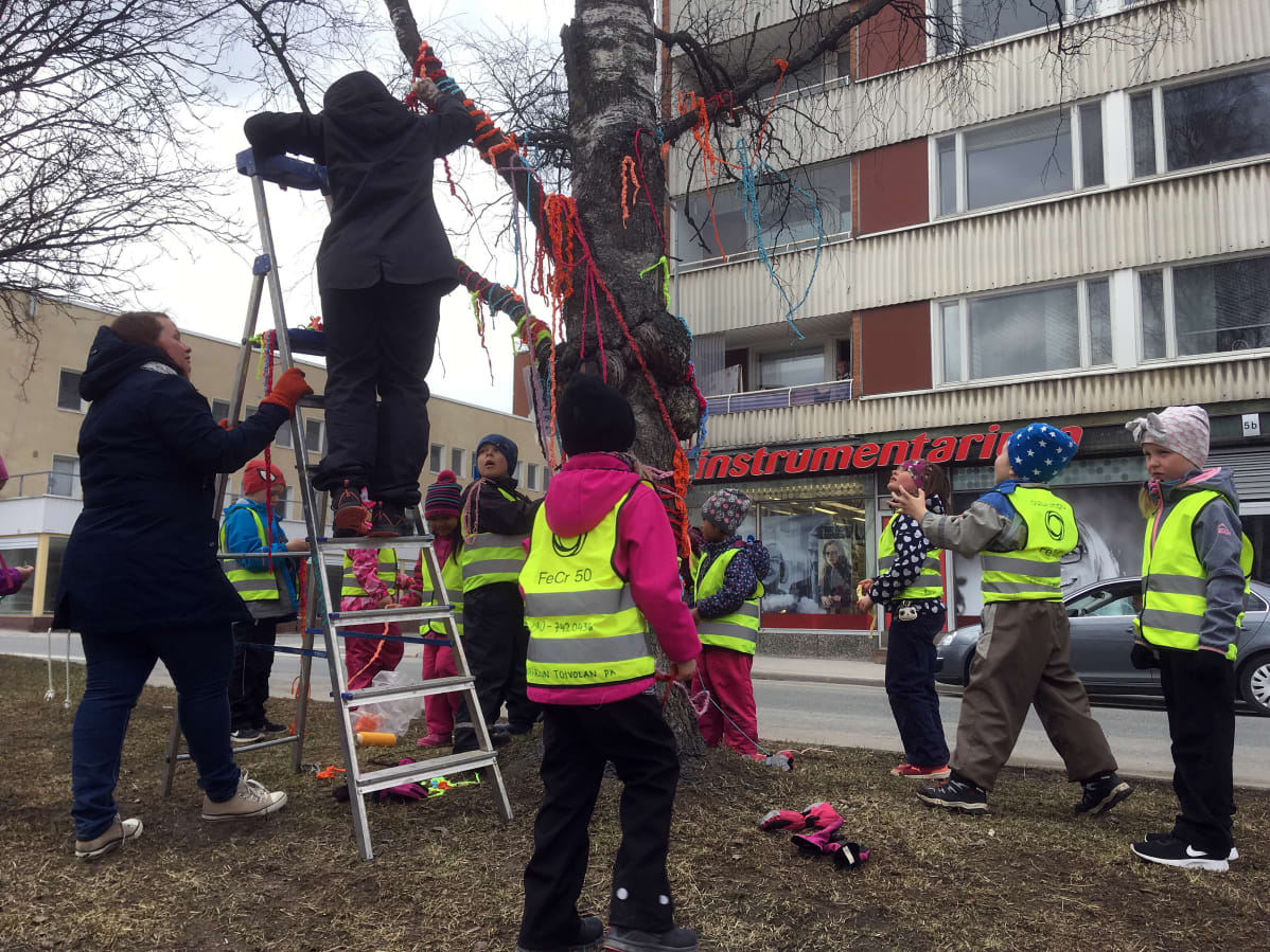 Esikoululaiset ja opettajat koristelevat puistokadun puita Kemissä.