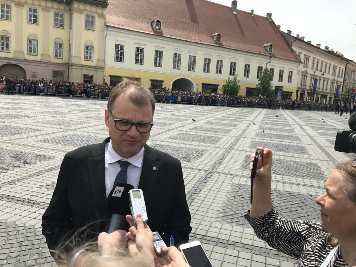Pääministeri Juha Sipilä haastateltavana. Hänen edessään on useita mikrofoneja.