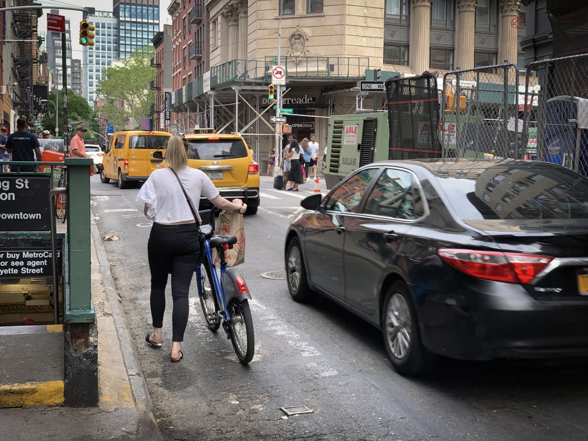 Nainen taluttaa pyöräänsä New Yorkissa.
