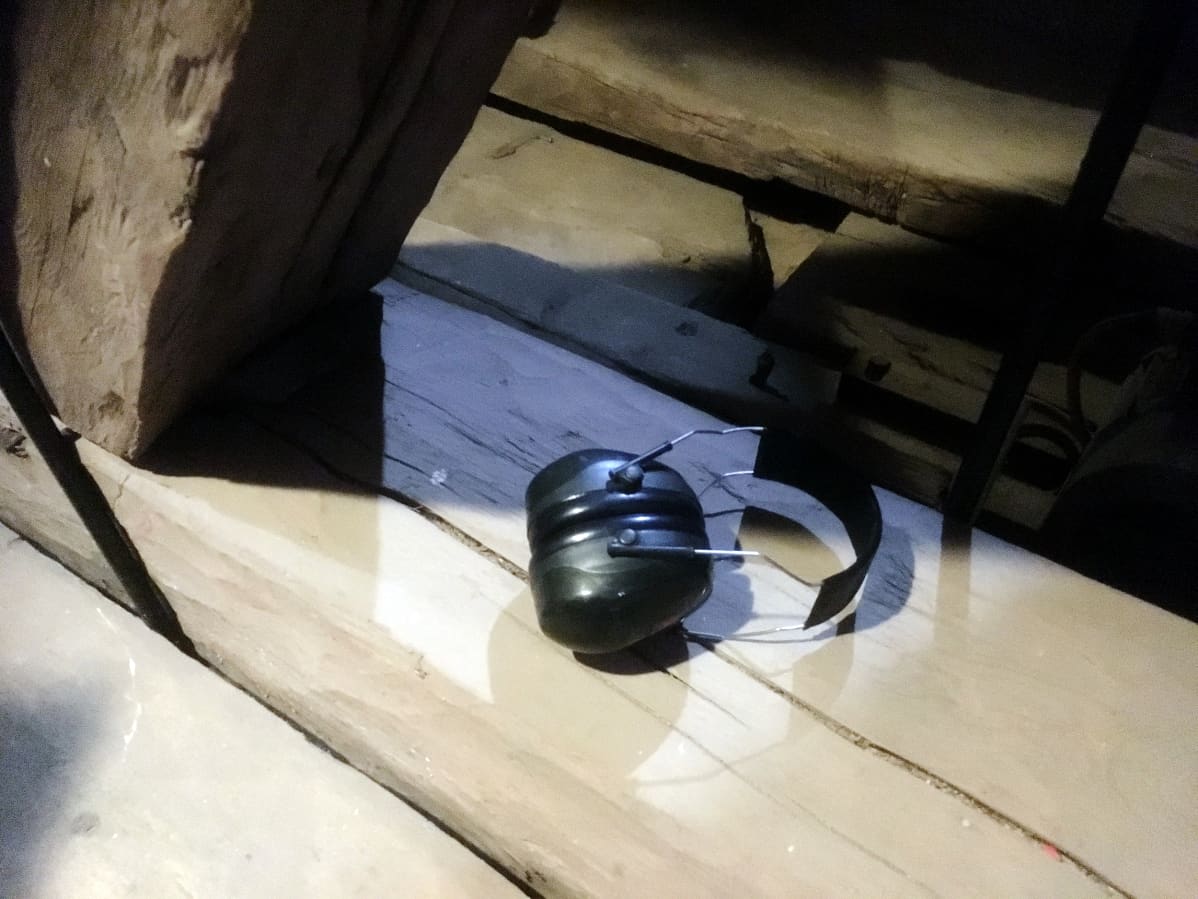 Kuulosuojat kirkon tapulin käsin veistetyistä lankuista tehdyn lattian päällä.