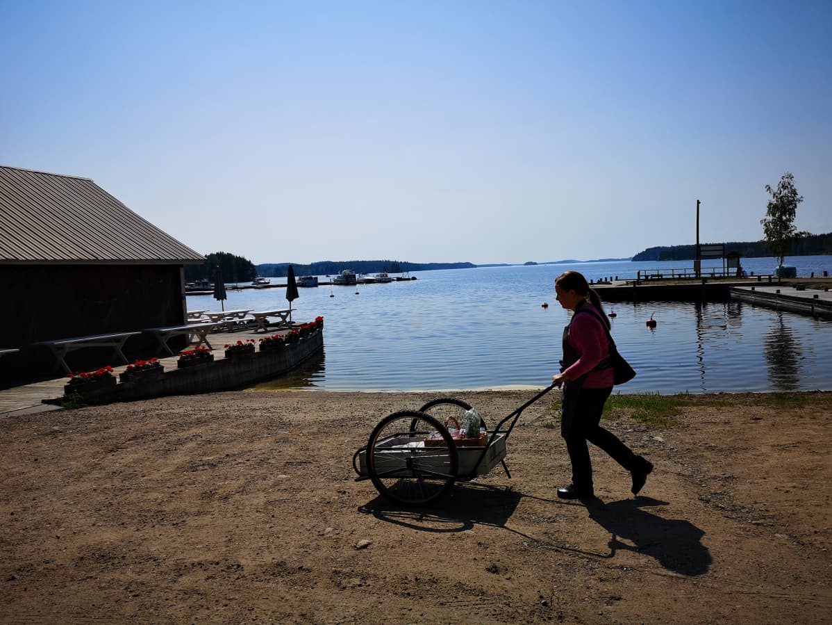 Nainen työntää kärryjä uimarannalla Puumalan Sahanlahdessa.