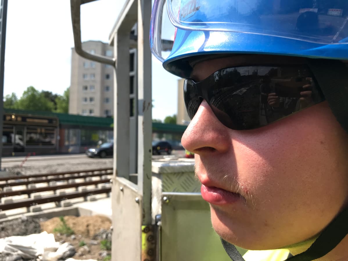 Mies suojakypärässä ja aurinkolaseissa, töissä ratikkatyömaalla.