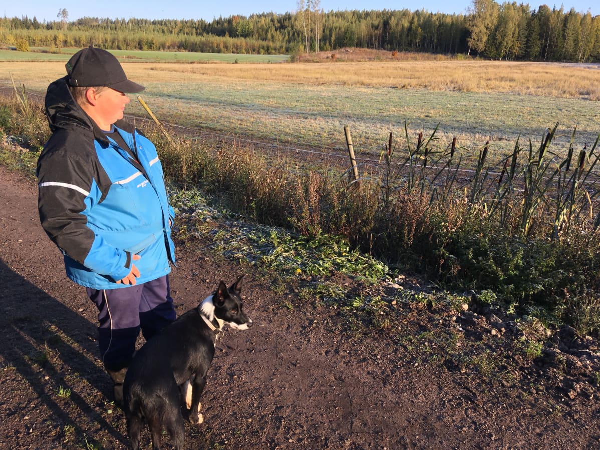 Pirjo Vanhala seisoo koiransa kanssa lammasaitauksen vieressä