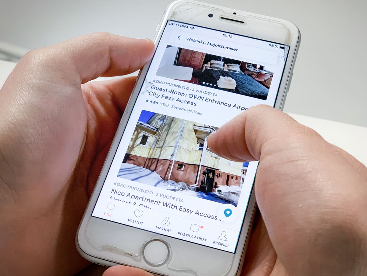 Mies selaileen kännykällä Airbnb tarjontaa.