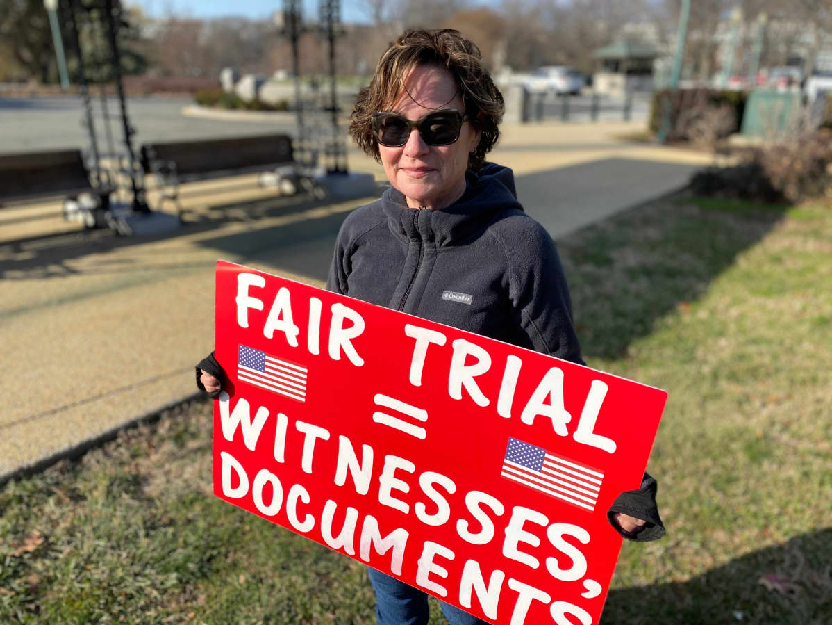 nainen ja kyltti, jossa lukee "fair trial = witnesses, documents"