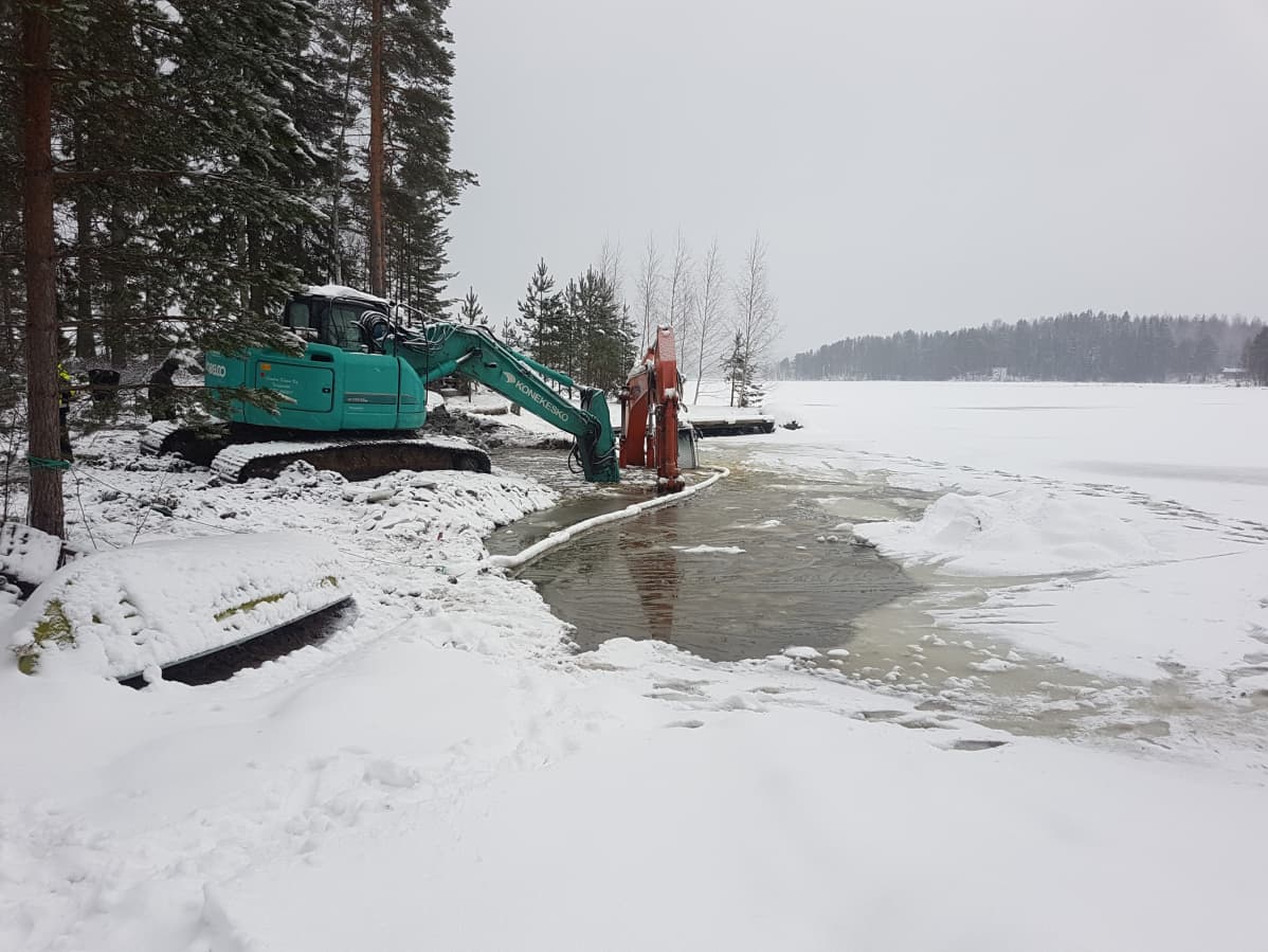 Kaivinkone Päijänteen rannassa kauhoo osittain uponnutta ruoppauskonetta.