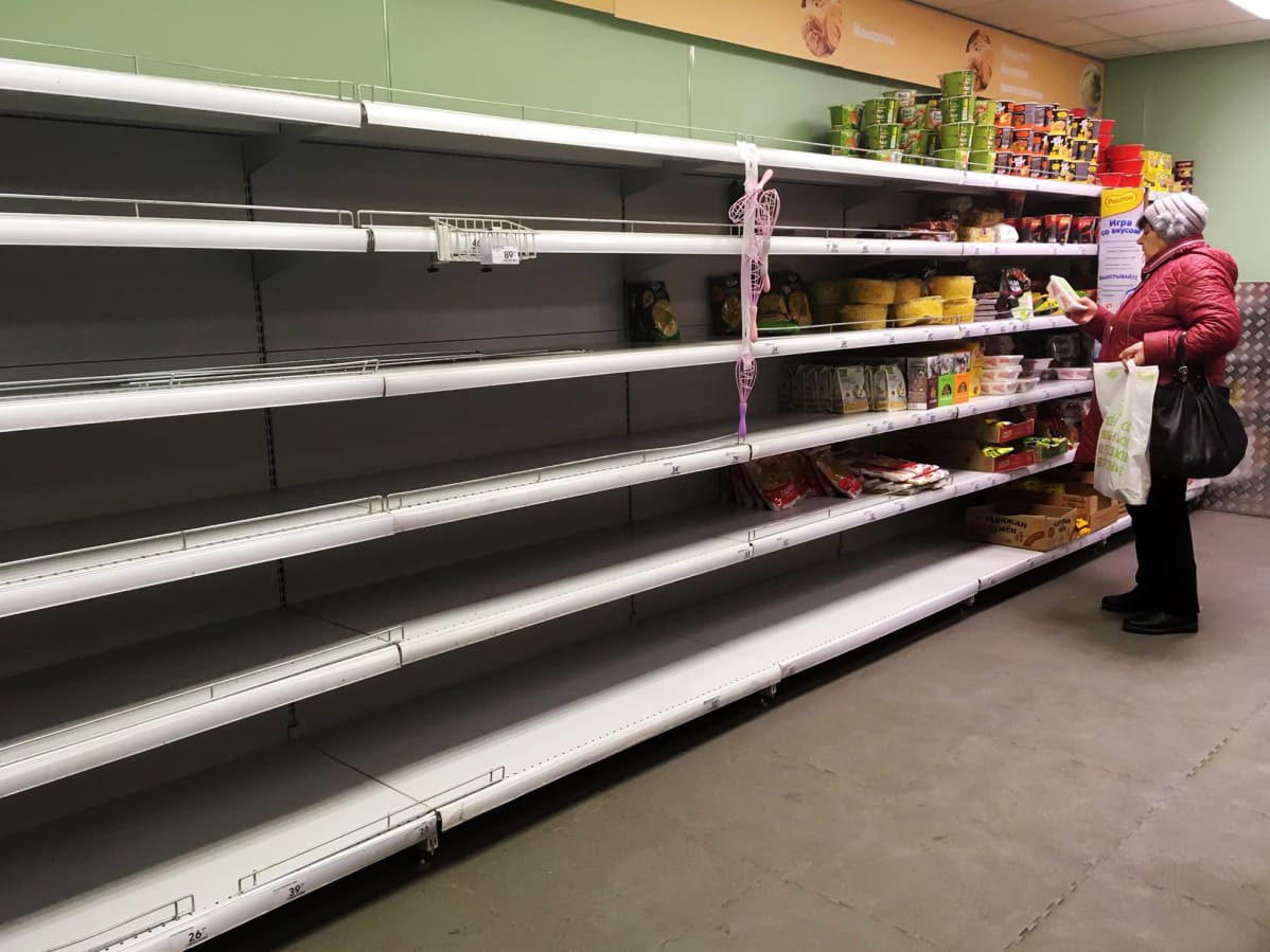 Kuvassa on nainen moskovalaisessa supermarketissa, jonka hyllyt ovat tyhjentyneet.