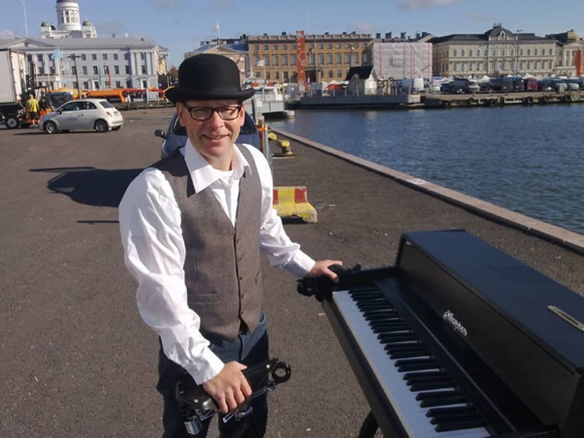 Mies esittelee soitintaan Helsingin kauppatorin laidalla.